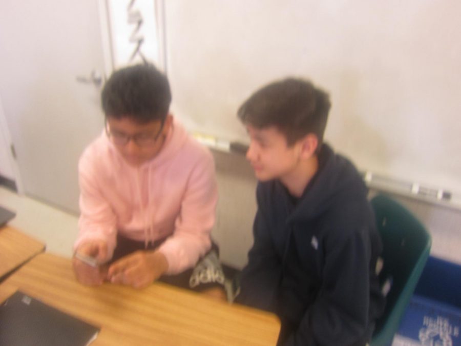 Tanishq Nerkar shows Ansel Morrill something on social media during class.