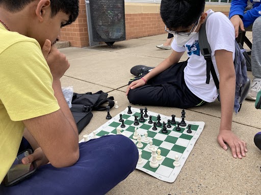 Daksh Dudipala (left) and Yash Date play a friendly game of chess outside the cafeteria while waiting for the next round to begin.