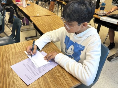Taher Nalwala, an eighth-grader on the Discovery team, fills out an envelope for his Civics LAA letter to be sent to his chosen government official.