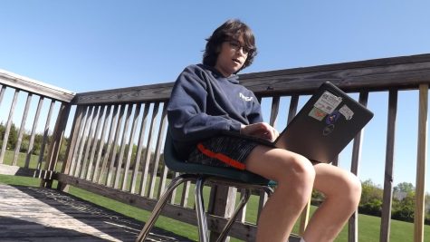 Roman Moreno-Hines, an eighth-grader works outside on his laptop.