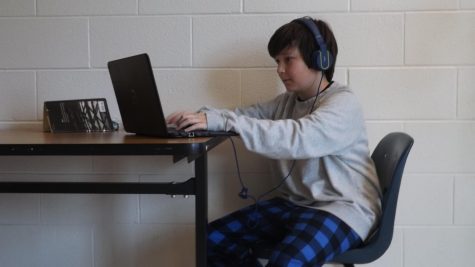 Seventh grade Mavericks student, Charlie Curtis working on his computer while wearing pajama pants.
