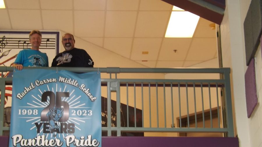 Mr. Kirk Treakle, librarian, and Mr. Moosa Shah, retired science teacher, share a smile by the 25th anniversary sign.