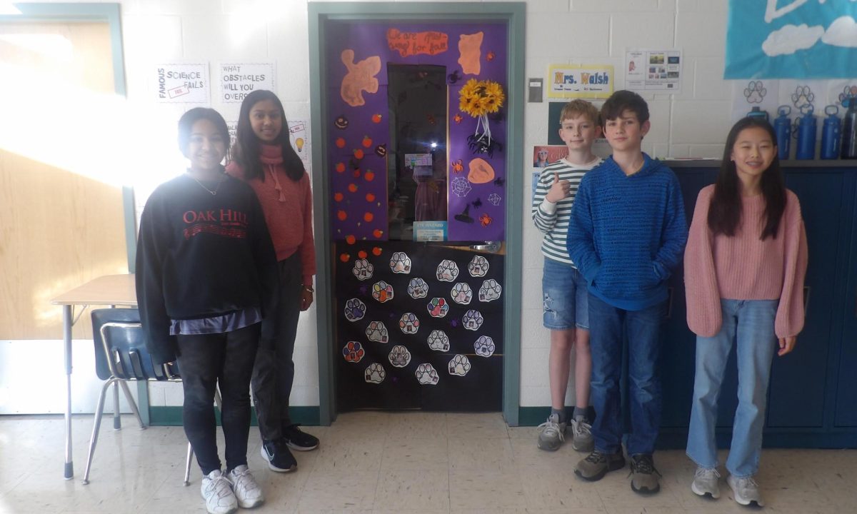 A picture of Ms. Patricia Walsh’s students next to their fully completed door with their decorations.
