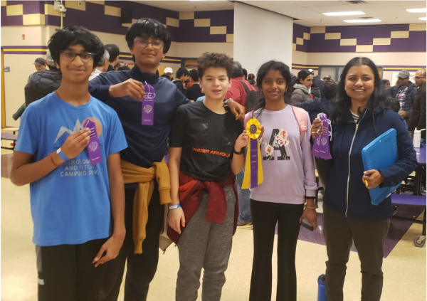 Some RCMS Science Olympiad members show their awarded ribbons while Coach Nithilaselvan (right) holds ribbons earned by other students in the Lake Braddock Invitational.