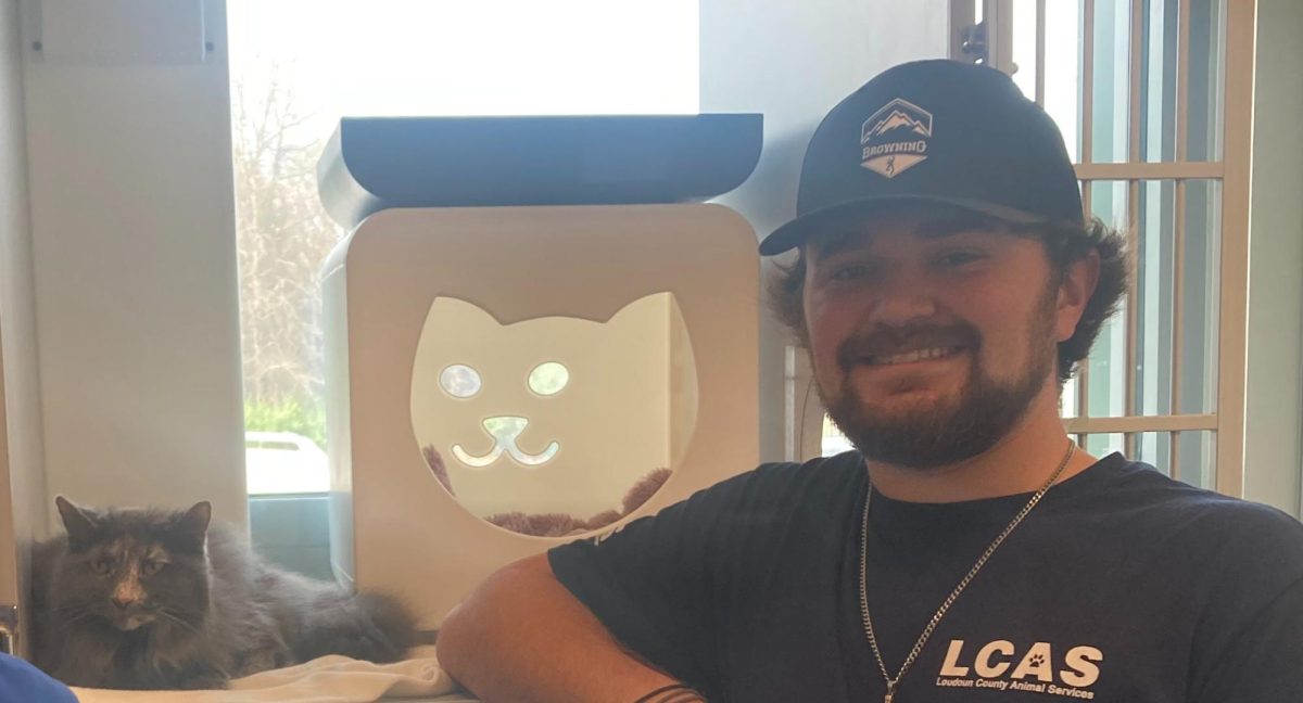 Zach Carpenter, an LCAS staff member, stands next to a cat that is available for adoption.