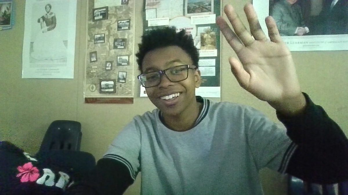 Jordan Williams waving out towards camera in classroom