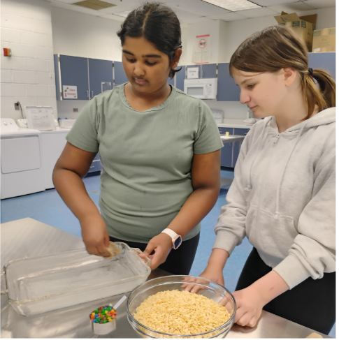 Lydia Thomas, a seventh-grader on the Legacy team, and Lara Schell, a seventh-grader on the Majestics team, making Rice Krispy Treats with M&M's at Cooking Club.
