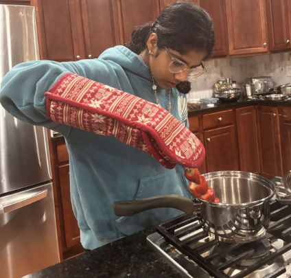 Seventh-grader Serafina Joseph dips a strawberry fruit stick on May 1 in her kitchen into boiling sugar.
